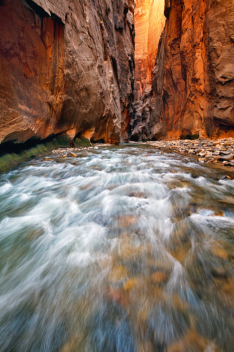 Incredible light makes its way through a dark passage deep in a swift moving section of the Narrows at Zion National Park, UT...