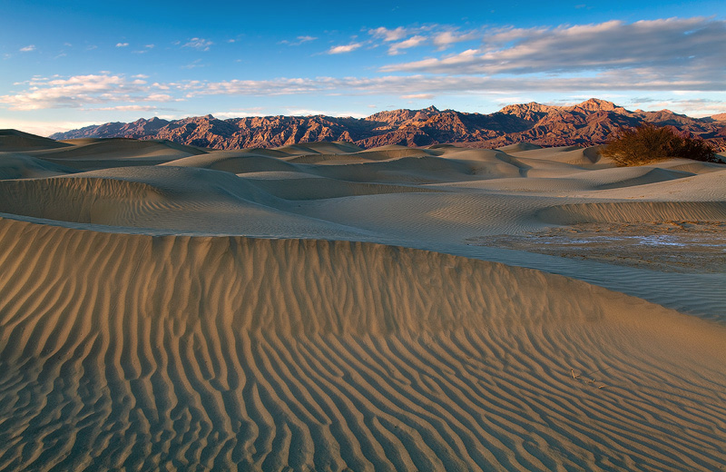 Late afternoon sunlight illuminates the flowing dunes of Mesquite Flats&nbsp;&nbsp;and cloaks the Grapevine Mountains as clouds...
