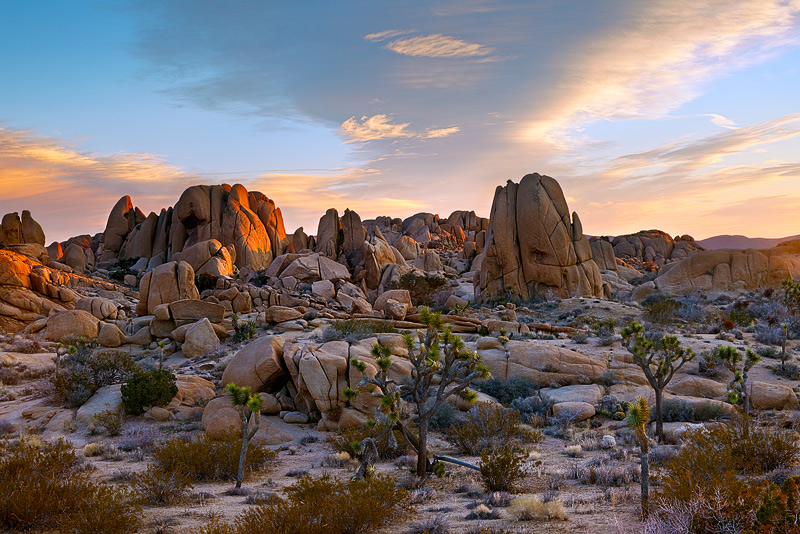 A colorful sunrise accentuates the rocky and barren landscape of the Mohave Desert in Joshua Tree National Park near the Jumbo...